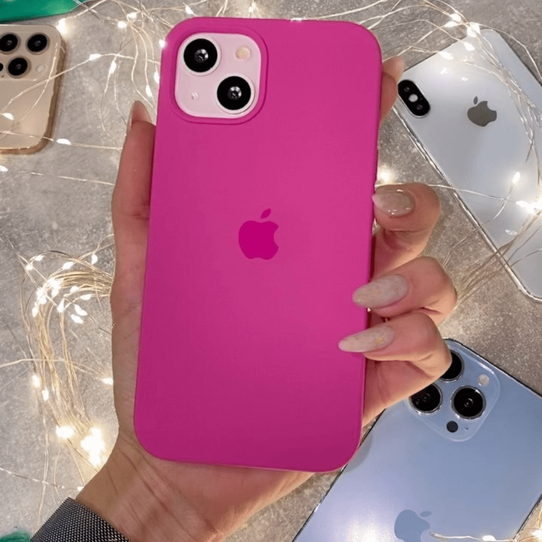 Hand holding a pink phone case with Apple logo against a blurred background of other phones.