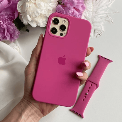 Hand holding a pink phone case with an Apple logo, next to a matching pink watch strap on a light background with flowers.