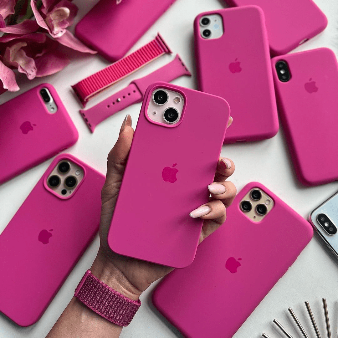 Person holding a pink phone case with multiple pink phone cases and accessories on a white background
